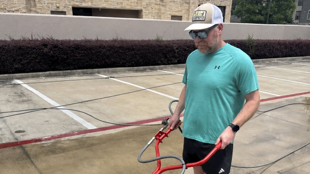 Brandon Wakeland running a surface cleaner on a commercial parking structure deck